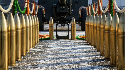 Artillery shells lined up in a ceremonial display with a large cannon in the background.