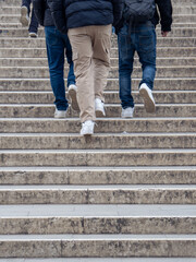 A low-angle shot of three people walking up outdoor stone steps