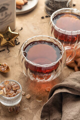 Black tea in two transparent glass cups on brown textured table background close up. Cozy breakfast teatime