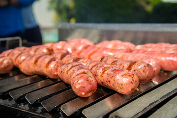 Sausages and meat cooking on outdoor barbecue grill
