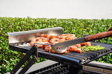 Grilling sausages and asparagus on outdoor barbecue