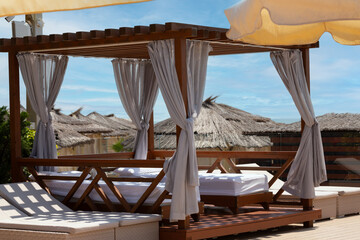 White beach canopy. Luxury beach tents with white curtains at the resort. Summer vacation concept. Beach bungalows in Sochi, Mandarin Beach, Adler, Russia