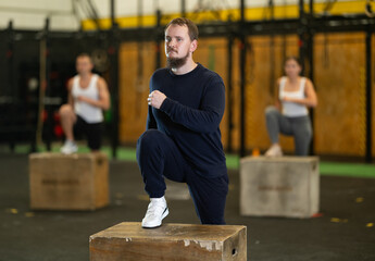 Active young man engaged in box step-up workout during weight training classes