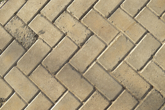 Piso de cal&ccedil;ada com blocos de pedra cinza em padr&atilde;o de ziguezague visto de cima