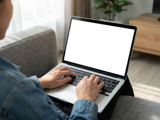 Laptop mockup with blank white screen for website or branding display. Person working from home on a couch in living room.