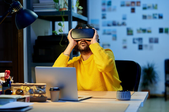 Man using virtual reality glasses and laptop in the office.