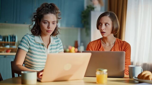 Two losers watching laptop sitting apartment kitchen closeup. Stressed brunette
