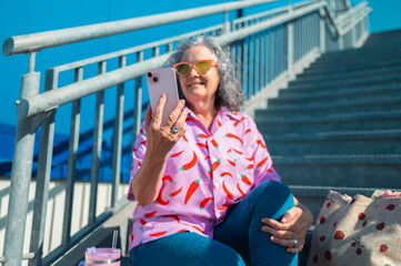 Senior woman with smartphone while sitting on stairs