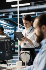 Engineer using tablet in data center to deploy server virtualization updates, configuring equipment...