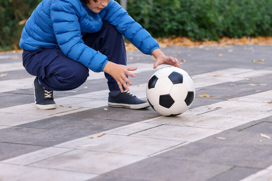 Little boy catching ball on pedestrian crossing outdoors, closeup with space for text. Child in danger and road safety
