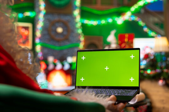 Close up of Santa Claus using maps on chroma key laptop to monitor toy shipments worldwide. Saint Nicholas follows global gift deliveries with interactive tracking tools on isolated screen notebook