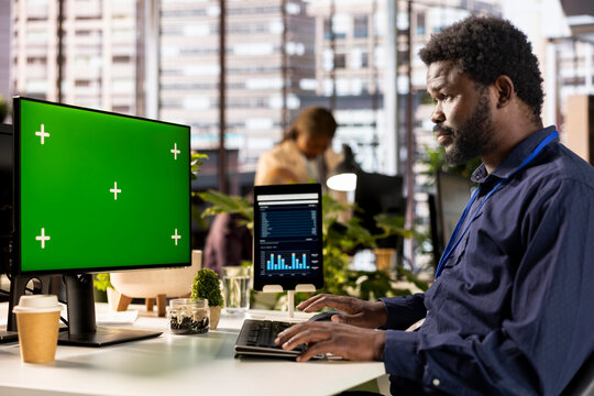African american office worker verifying data analytics with copy space, using monthly infographics to create a financial report. Young man collecting performance metrics on computer.