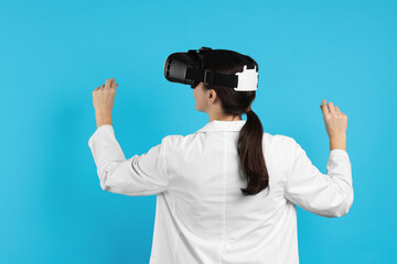 Modern technology. Doctor in headset using virtual screen on light blue background, back view