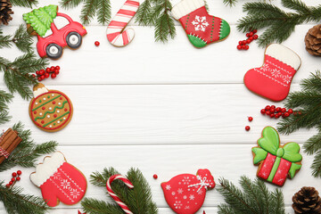 Frame made of tasty gingerbread cookies and Christmas decor on white wooden table, flat lay. Space...