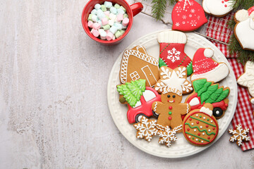 Tasty gingerbread cookies, marshmallows and Christmas decor on white textured table, flat lay. Space for text