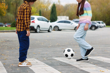 Little girl and boy playing with ball on pedestrian crossing outdoors, closeup. Children in danger and road safety
