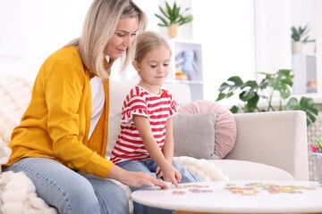 Naklejka premium Mother teaching her daughter alphabet at white table indoors