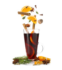 Mulled wine. Spices and orange slices falling into glass cup of hot beverage on white background