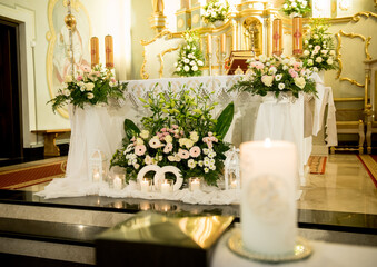 Elegant floral wedding altar in a Catholic church with candles, white lanterns and intertwined rings symbolizing love and holy matrimony