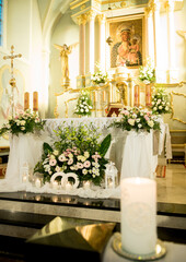 Vertical wedding altar in Catholic church with floral arrangements, candles, lanterns and religious...