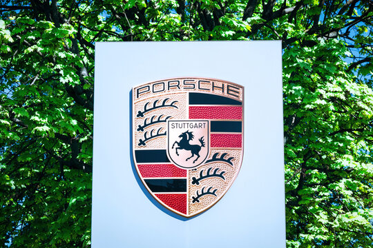 Poznan, Poland - April 26, 2025: Porsche logo on a pylon with green trees in the background.