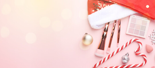Christmas banner with makeup products, Santa hat and festive balls on pink background, flat lay