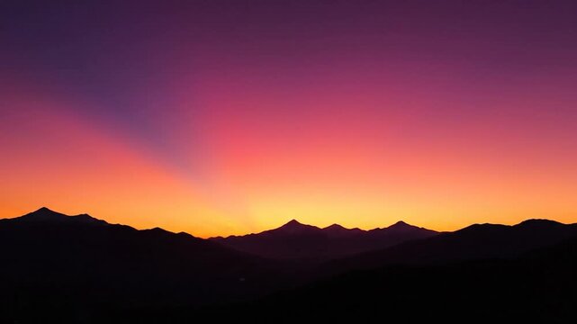 Vibrant sunset over silhouetted mountains with a colorful gradient sky