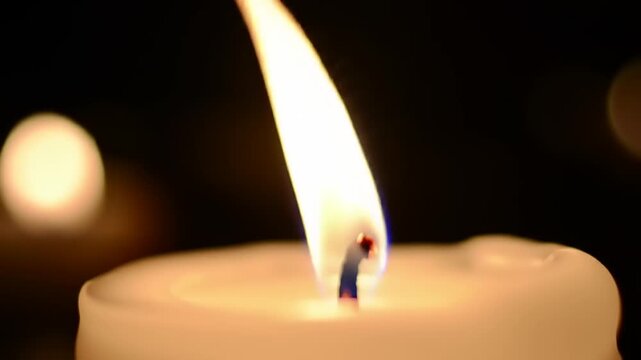 Lit candle flame closeup on dark background.