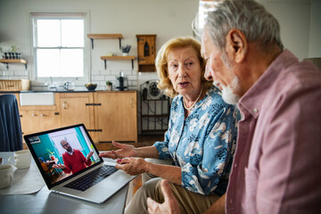 Senior couple on video call expressing concern in home kitchen