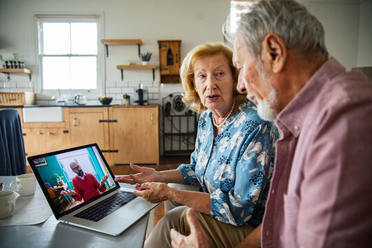 Senior couple on video call expressing concern in home kitchen