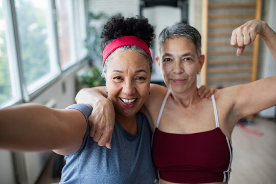 Mature lesbian couple taking happy fitness selfie at home - Powered by Adobe