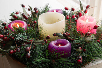 Close up advent wreath with four candles lit on a white table