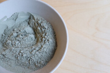 Close-up of a bowl of green clay with a wooden spoon. Healing with green clay. Skin mask with green clay. and well-being.