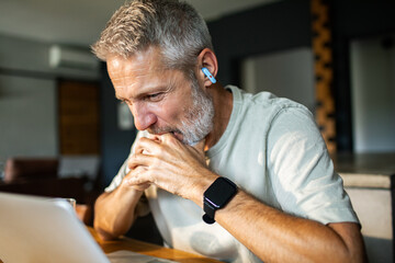Mature man focused while working on laptop at home
