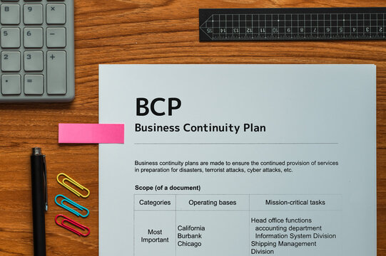 The dummy document of the Business Continuity Plan is on the desk, along with a calculator and a pen.
