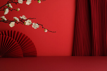 White blossoms over a red fan with deep red pleated curtains and red stage.