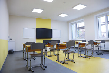 Stylish classroom with desks, chairs and tv at school