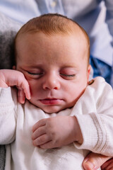 Newborn baby sleeping peacefully on caregiver's arm