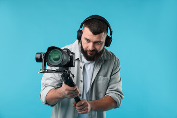 Videographer using gimbal stabilizer with camera on light blue background