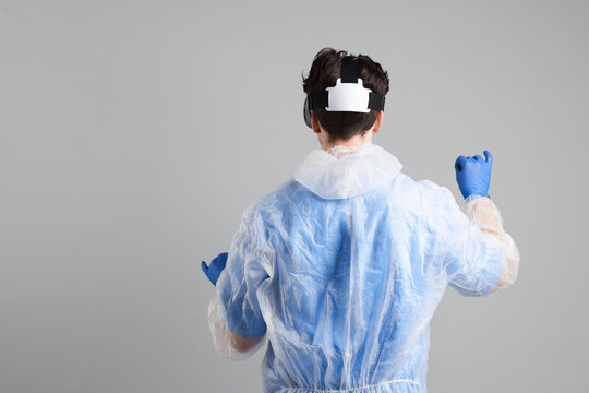 Modern technology. Doctor using virtual reality headset on grey background, back view. Space for text