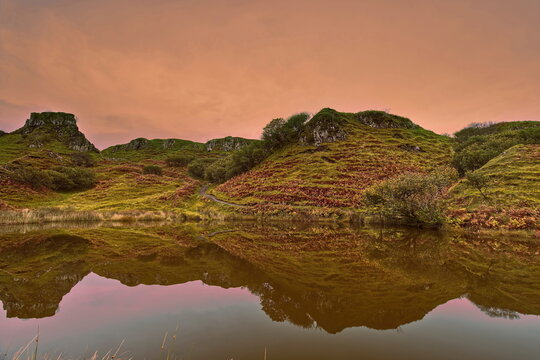 Rosy sky of late afternoon lighting the lochan at Fairy Glen, with the basalt outcrop of Castle Ewen reflected in the water. Isle of Skye-Scotland-120