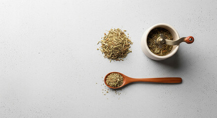 Top view of aromatic dried herbs, wooden spoon, and hand grinder for culinary use.