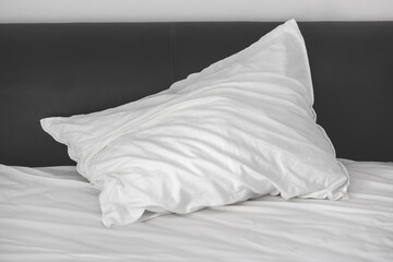 A crumpled white pillow lies on the bed after sleeping