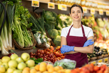 Portrait of female seller in apron in interior of grocery supermarket