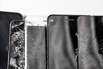 A pile of broken phones lies on a white background, many broken phones.