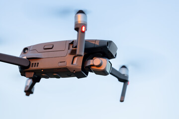 Drone hovering in the sky, unmanned aerial vehicle against blue sky