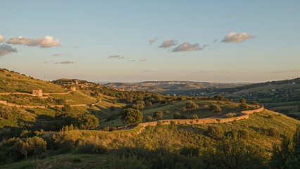 Obraz premium Lush green hills and farmland under a partly cloudy sky during the daytime.