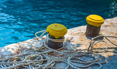 rope on yellow iron mooring bollard. sea background, Symi island,  Greece