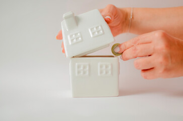 Woman saving coin in house piggy bank for investment