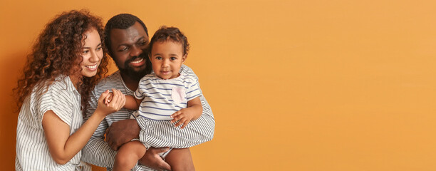 Happy African-American parents with cute baby on color background